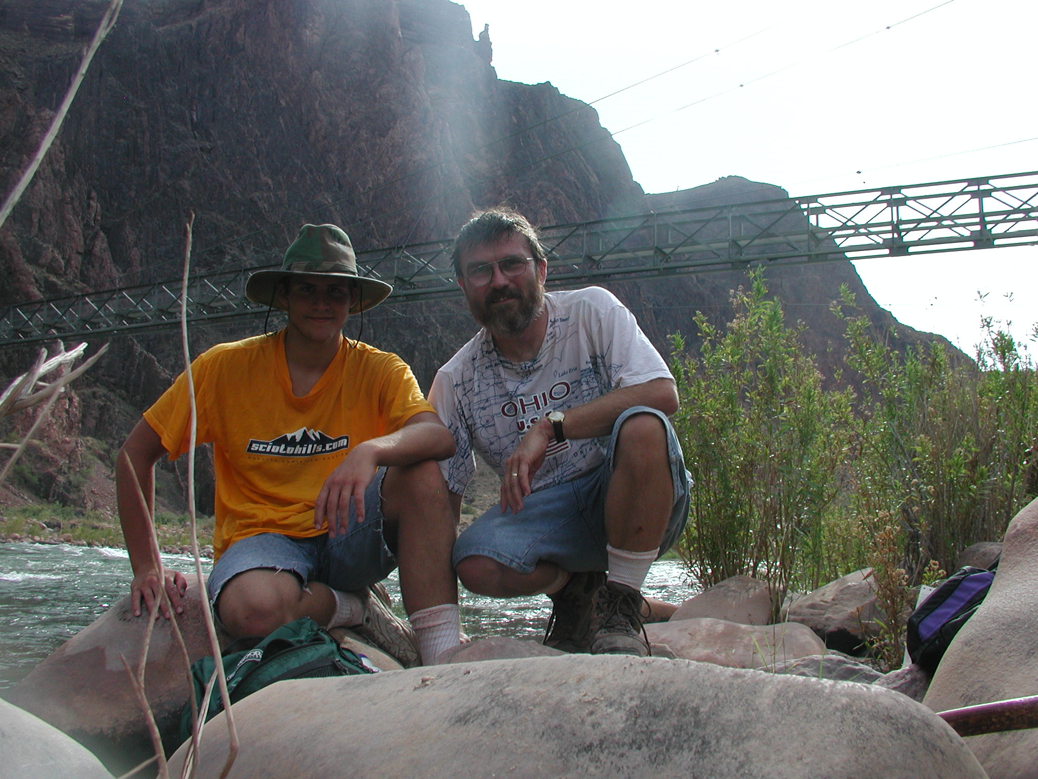 Doug and his son at the Colorado River near Phantom Ranch, the footbridge behind them — July 2003.